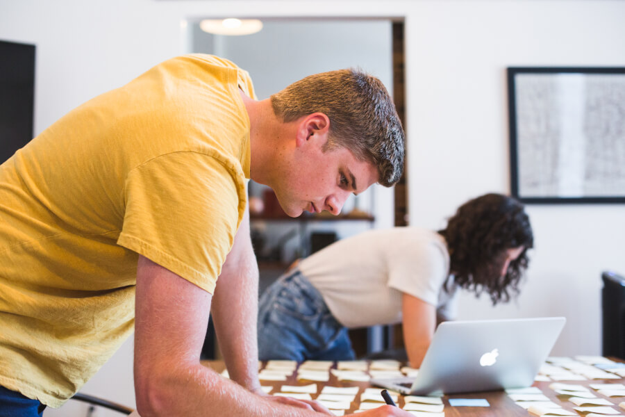 White male and female stood writing post-it notes at a table